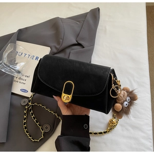 Détail du sac oreiller en similicuir noir avec fermoir doré et breloque en peluche