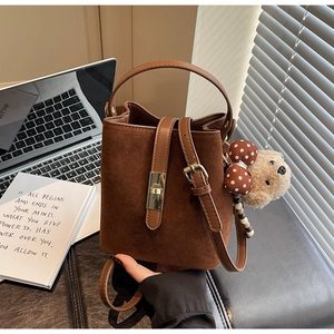 Détail du sac seau en daim marron avec fermoir doré et pendentif en forme d'ours