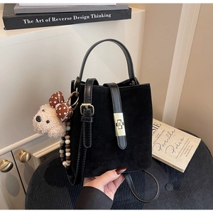 Détail du sac seau noir mat avec boucle en métal doré et pendentif ourson en peluche