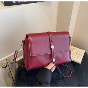 Close-up of wine red crossbody bag with silver buckle and smooth faux leather finish