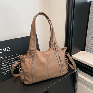 Detail of khaki pebbled leather tote bag featuring vertical zippers and adjustable strap