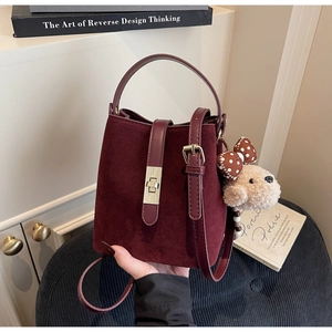 Détail du sac seau bordeaux mat avec bandoulière réglable et breloque ours en peluche