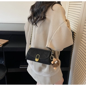 Détail du sac en daim noir avec serrure dorée et breloque monstre en peluche marron décor
