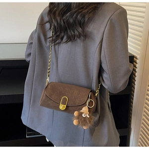 Détail du sac oreiller marron rétro en cuir avec chaîne dorée et bijou de sac