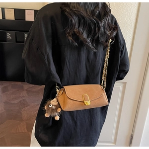 Détail du sac oreiller en daim camel avec bandoulière chaîne dorée et gri-gri