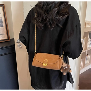 Sac oreiller en daim marron avec chaîne dorée et breloque peluche porté par un mannequin