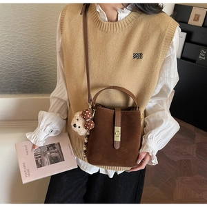 Détail du sac seau en daim marron foncé avec pendentif ours en peluche sur la bandoulière