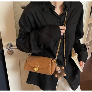 Détail d'un sac bandoulière en cuir marron avec serrure dorée et porte-clé hérisson