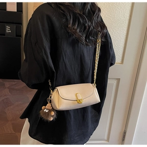 Détail du sac oreiller en cuir beige avec fermoir doré, chaîne métal et charme ours peluche
