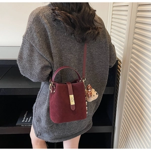 Détail du sac seau bordeaux mat avec fermoir doré et charmant petit ours