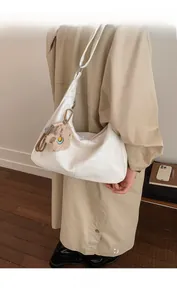 Detalle del bolso hobo blanco de cuero sintético con un lindo colgante de oso de peluche