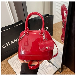 Detalle de un bolso de mano rojo estilo jelly brillante con mini monedero a juego
