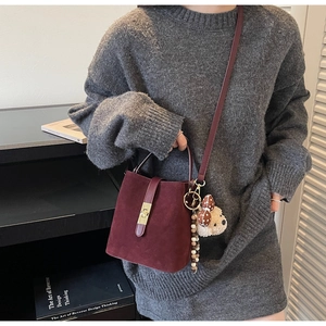 Détail du sac seau bordeaux en daim avec fermoir doré vintage et breloque petit ours
