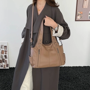 Detail of caramel leather tote bag with vertical zippers and adjustable strap