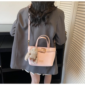 Détail du sac seau rose clair avec lanière en cuir et pendentif lapin en peluche