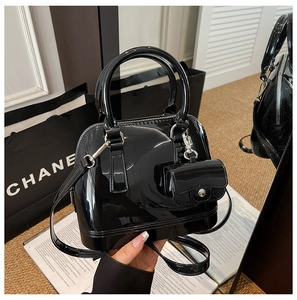 Detalle de bolso de charol negro brillante con mini bolsa de accesorios a juego