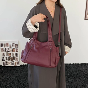 Detail view of burgundy tote bag with leather texture and vintage bronze metal zippers