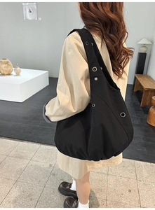 Detail of black nylon tote bag with metal eyelets showing the slouchy textured design