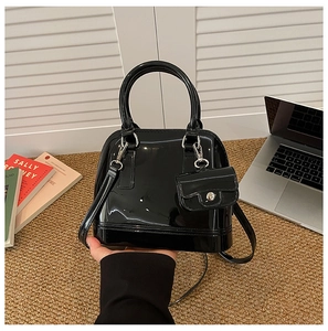 Detalle del bolso de mano negro brillante con forma de concha y monedero pequeño a juego