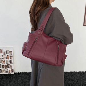 Macro view of vintage wine red tote bag showing soft leather texture and zipper pockets