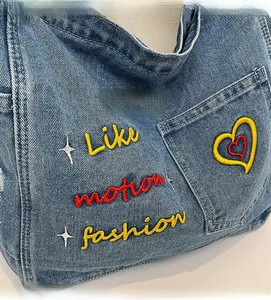 Detail of blue denim tote bag with colorful Like Motion Fashion letter embroidery
