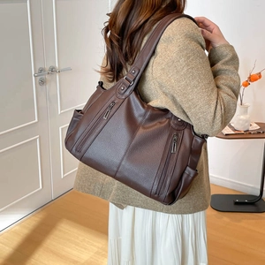 Detail of dark brown lychee grain tote bag with metal zippers and side pockets