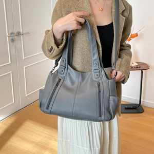 Detail of grey lychee leather tote bag showing side pockets and vertical zippers on model