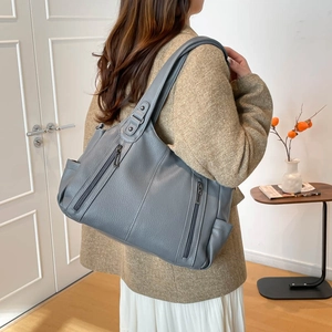 Detailed view of grey pebble leather tote bag featuring two vertical zipper pockets
