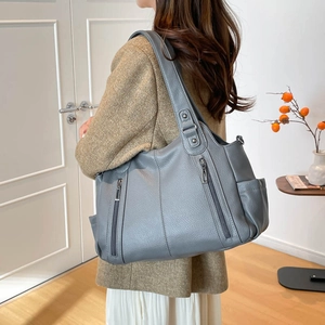 Detail of grey pebbled leather tote bag with vertical zipper pockets and silver hardware