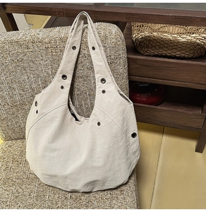 Close-up detail of beige hobo bag showing metal grommets and wrinkled nylon texture