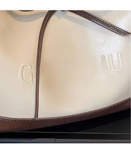 Detailopname van witte leren tas met bruin GONGZHU-logo en nette afwerking van de olieranden
