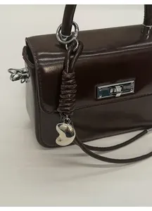 Detailansicht der dunkelbraunen Ledertasche mit Silberschloss und Herz-Anhänger