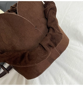 Close-up of the dark brown matte suede texture and unique pleated handle detail of the bag