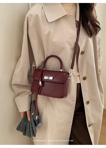 Detail of burgundy leather handbag featuring silver twist-lock and elegant knot charm