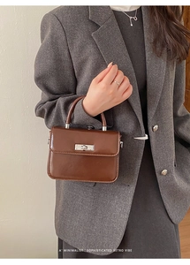 Minimalistische Retro-Handtasche in Dunkelbraun, präsentiert mit einem grauen Blazer
