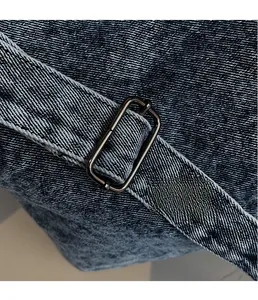 Detail of premium metal buckle and dark blue denim texture on the shoulder strap