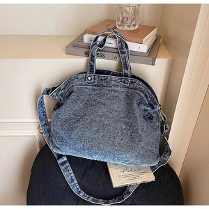 Detail view of washed denim tote bag showing vintage blue texture and rivet accents