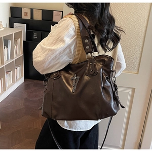 Dettaglio della borsa tote vintage in pelle marrone con ciondolo a croce e catenella