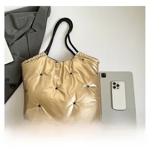 Detail of gold quilted tote bag featuring black star patterns and black tubular handles