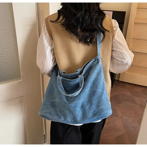 Blue denim tote bag with wide shoulder strap showing large capacity and wash texture