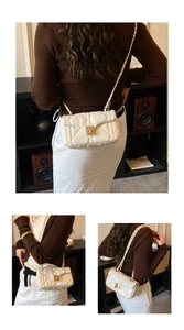 Detail of cream quilted crossbody bag featuring gold chain strap and metal lock closure
