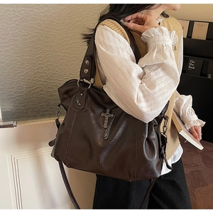 Dettaglio della borsa tote marrone scuro con croce in metallo e catena in stile lifestyle