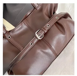 Detailaufnahme der dunkelbraunen PU-Ledertasche mit dekorativer Gürtelschnalle und Metallösen