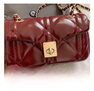Detail of burgundy quilted leather bag with gold twist lock and chain strap