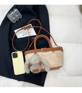 Détail du sac seau en paille avec garniture en cuir brun et charm lapin en peluche