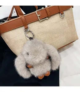 Détail d'un pendentif lapin en peluche grise avec crochet en métal sur un sac tissé