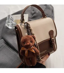 Detail of vintage patchwork leather handbag featuring a cute plush bear charm accessory