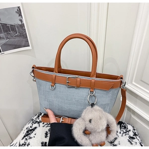 Détail du sac seau en tissu bleu clair avec anses en cuir marron et pendentif lapin