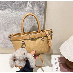 Détail du sac cabas tissé kaki avec garniture en cuir et accessoire lapin en peluche