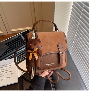 Close-up of a vintage brown PU leather crossbody bag with a cute plush bear pendant